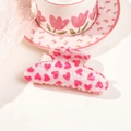 Detail einer rosa Herz-Haarklammer aus Acryl auf einer dekorativen Untertasse - 10,5 cm Bogen - Rosa mit weißem Herz