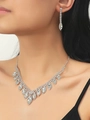 Detailed view of elegant silver rhinestone necklace and earring set worn by a model - White