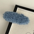 Close-up of a blue plush faux shearling hair clip displayed in a black frame - Blue