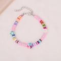 Buntes handgefertigtes Boho-Perlenarmband mit Herz- und Sternanhängern auf Stoffhintergrund - Rosa