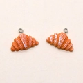 Dettaglio di ciondoli a forma di croissant in resina con glassa e anelli metallici - Croissant