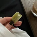 Close-up of vintage emerald green acetate semicircle charm on a black elastic hair tie - Wide Bean Green