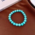 Macro detail of turquoise beads bracelet with natural textures on brown fabric backdrop - 8mm / Blue