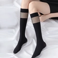 Black JK Lolita knee high socks with lace-up hollow mesh panels on white bed background - Black Hollow Mesh Calf Socks