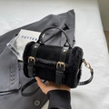 Schwarze Handtasche aus Kunstpelz und mattem Leder mit dekorativen Schnallenriemen - Schwarz