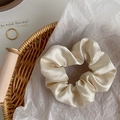 Close-up of champagne satin scrunchie with crystal details in a woven basket - Satin Cream