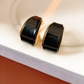 Dettaglio di orecchini curvi in resina nera con bordi placcati oro su supporto bianco - Orecchini a Cerchio-Nero (Placcato Oro Vero)