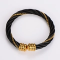 Close-up of twisted black steel cable bracelet with gold chain detail and threaded beads - Black Gold with Square Details