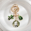 Cute panda and bamboo metal keychain with gold enamel finish on a white ceramic plate - Panda Eating Bamboo V2