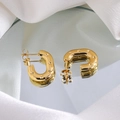 Detailed view of gold horseshoe earrings with star engravings on a silk reflective surface - Gold Star Embossed Hoop