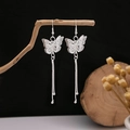Macro detail of silver butterfly earrings with long tassels on a natural branch - Butterfly Hollow Long Tassel Style (E4252-1)
