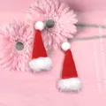 Vue détaillée de mini bonnets de Noël rouges en tricot avec pompons sur fond rose doux - Mini Bonnet de Noël à Bord Brut (Unique)
