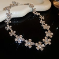 Macro view of silver floral necklace with sparkling zircon petals on dark surface - Flower Necklace