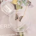 Close-up of a gold butterfly necklace with smoky translucent wings and micro-inlaid stones - Gray