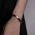 Close-up of polished gold-plated stainless steel hinged bangle worn on the wrist - 4mm / Gold