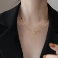 Elegant gold necklace featuring rectangular crystals and tassels worn on a business blazer - Gold