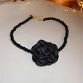 Detail of elegant black fabric camellia pendant with beaded chain on ceramic plate - Black Flower Pearl Necklace