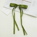 Close-up of elegant forest green satin bow hair clip with flowing ribbon on nature book - Turquoise Green