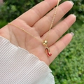 Vergulde ketting met rode polka dot high heel hanger vastgehouden in de hand - Rode Gestippelde Hoge Hakken
