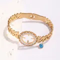 Gold titanium steel bracelet with evil eye charm and hollow heart detailing - Turntable Hollow Style