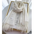 Detail of cream white knit cashmere scarf with soft tassel edges and woven brand label - Cream