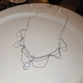 Detailed macro view of the large white pearl and rhinestone lace pendant on a ceramic dish - 28# Silver Fan Rhinestone Pearl Necklace