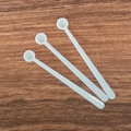 Three long-handled white plastic measuring spoons for milk powder on a wooden table - 0.15ml Long Handle (8.3*1*0.52cm) / White