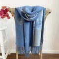 Blue and grey cashmere scarf with dandelion patterns and tassels on a wooden chair - Dandelion Blue