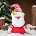 Cute Santa Claus plush doll with red knitted body and striped hat in a winter scene - Santa Claus