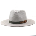 Close-up of olive green fabric band and leather strap with brass rings on a straw hat - Gray