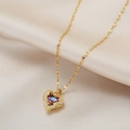 Collier pendentif cœur doré avec pierre colorée et chaîne pétale sur tissu beige - Cœur de l'Océan