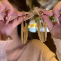 Nahaufnahme eleganter goldener Quastenohrringe mit langen Fransen und Vintage-Details - Gold