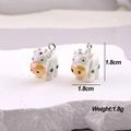 Macro view of pearlescent white cow charms with golden noses on white textured stones - AB Colorful Cow