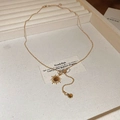 Macro detail of 18K gold plated necklace with sunburst pendant and brown tiger eye stone - Gold Brown