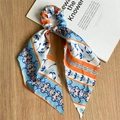 Close-up of floral satin hair scrunchie with long ribbons on light wood background - Blue & Orange Satin Ribbon