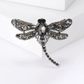 Detailed studio shot of a dragonfly brooch featuring black and grey crystal accents - Gray