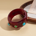 Macro detail of vintage resin bangle with embedded turquoise and faceted gemstones - Bohemian Gemstone Inlaid Style