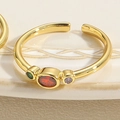 Macro detail of gold open ring with red oval stone and green and purple side gems - Adjustable Open / Red Oval Zirconia Style (JZ0333)
