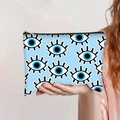 Detail of light blue Evil Eye printed canvas makeup bag held by a model for size scale - Light Blue Repeating Evil Eye (jiaying0034)