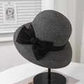 Close-up of grey straw sun hat featuring a large black satin bow on metal stand - 57.5cm (Adjustable) / Black (Satin Bow)