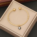 Detail van de gouden roestvrijstalen open armband met een boos oog bedeltje in doos - Zwart