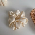 Elegant cream beige satin silk scrunchie with soft fabric folds in minimalist style - Off White