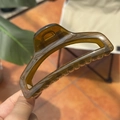 Detailed macro view of an amber resin hair claw clip showing a clear texture in sunlight - Jelly Yellow Green