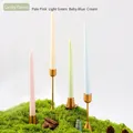 Velas cónicas en rosa, verde, azul y crema sobre elegantes candelabros dorados - Colores de Caramelos