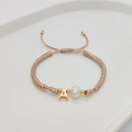 Close-up of handmade woven bracelet with white pearl and gold letter A charm on tray - Letter A