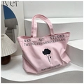 Detail of pink canvas tote bag with black floral print and NKK Art Studio typography - Pink
