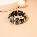 Dettaglio di blocchi di resina marmorizzata e distanziali dorati su bracciale elastico - Nero