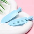 Close-up of two light blue matte finish metal hair clips on a soft pink background - Blue - Glossy without Letters