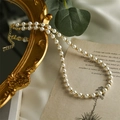 Detailopname van parelketting met gouden kralen op vintage spiegel en eucalyptus - Afwisselende parel en metalen kraal