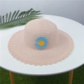 Vue détaillée d'un chapeau de paille rose orné d'une marguerite bleue au crochet. - Adulte M (56-58cm) / Marguerite à Bord Festonné / Rose Clair